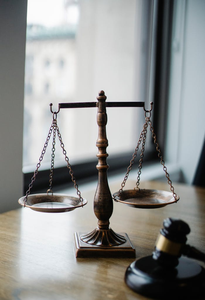 pexels photo 5669602 Decorative judgement scale and gavel placed on desk in light lawyer office against window