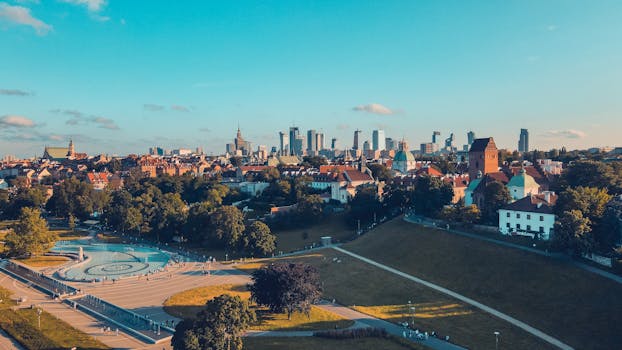 Możliwość przyjmowania spraw spoza rewiru w 2025 r. Stunning aerial shot of Warsaw skyline and park under a bright blue sky.